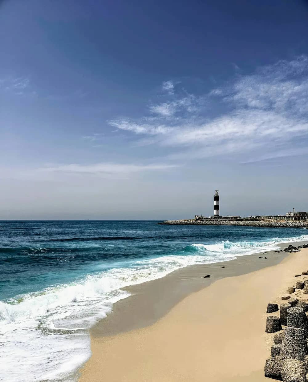 A sandy beach with the lighthouse in the distance