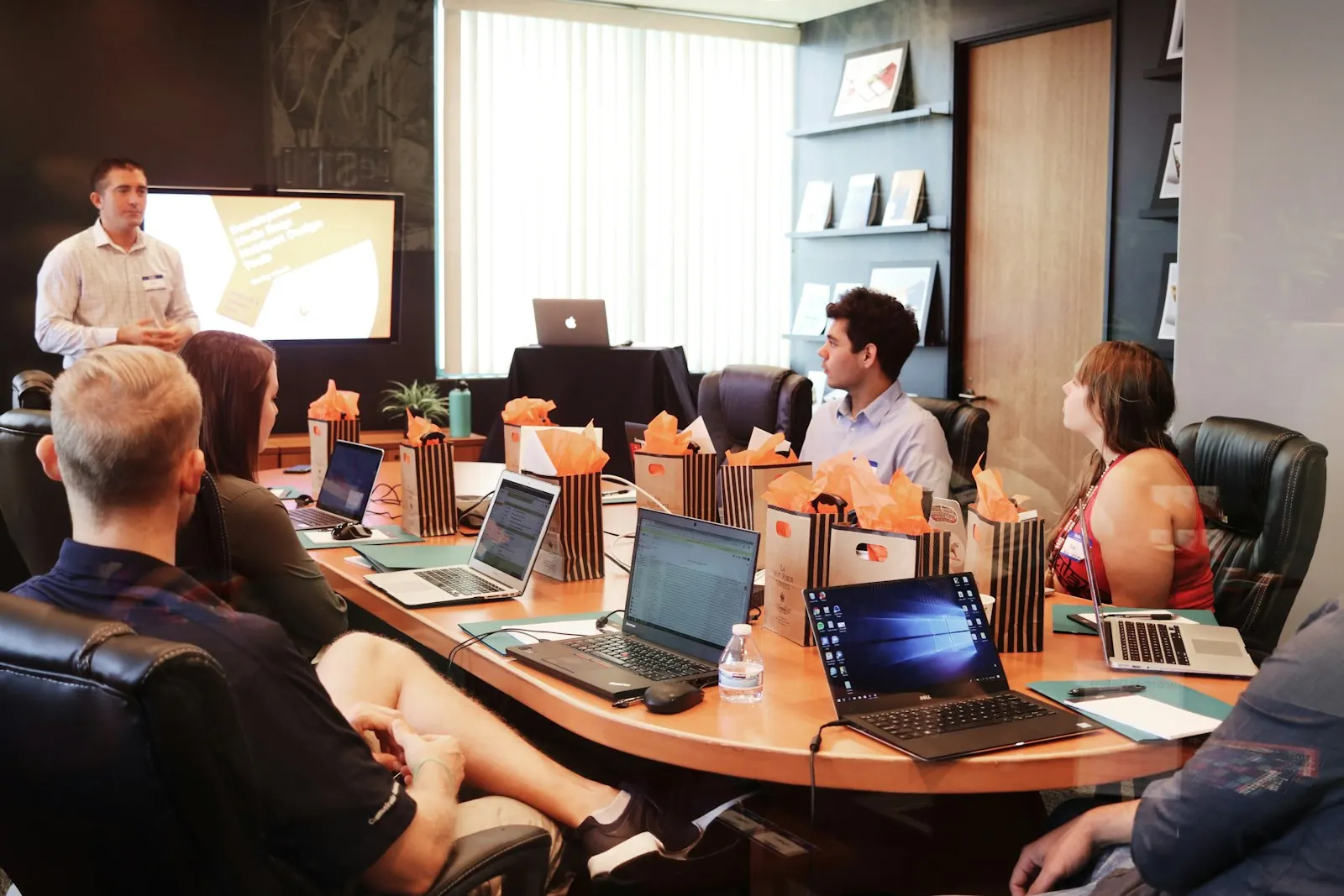 A presenter speaking to a group seated around a boardroom table