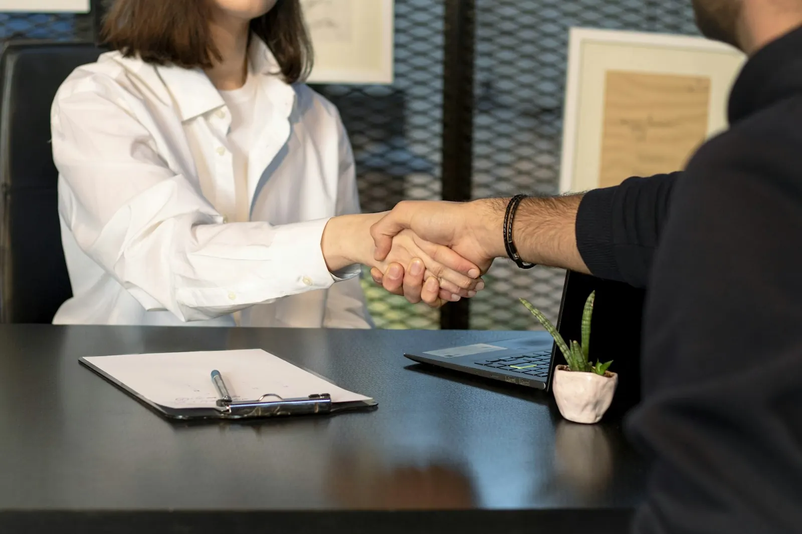 Two people shaking hands across a desk