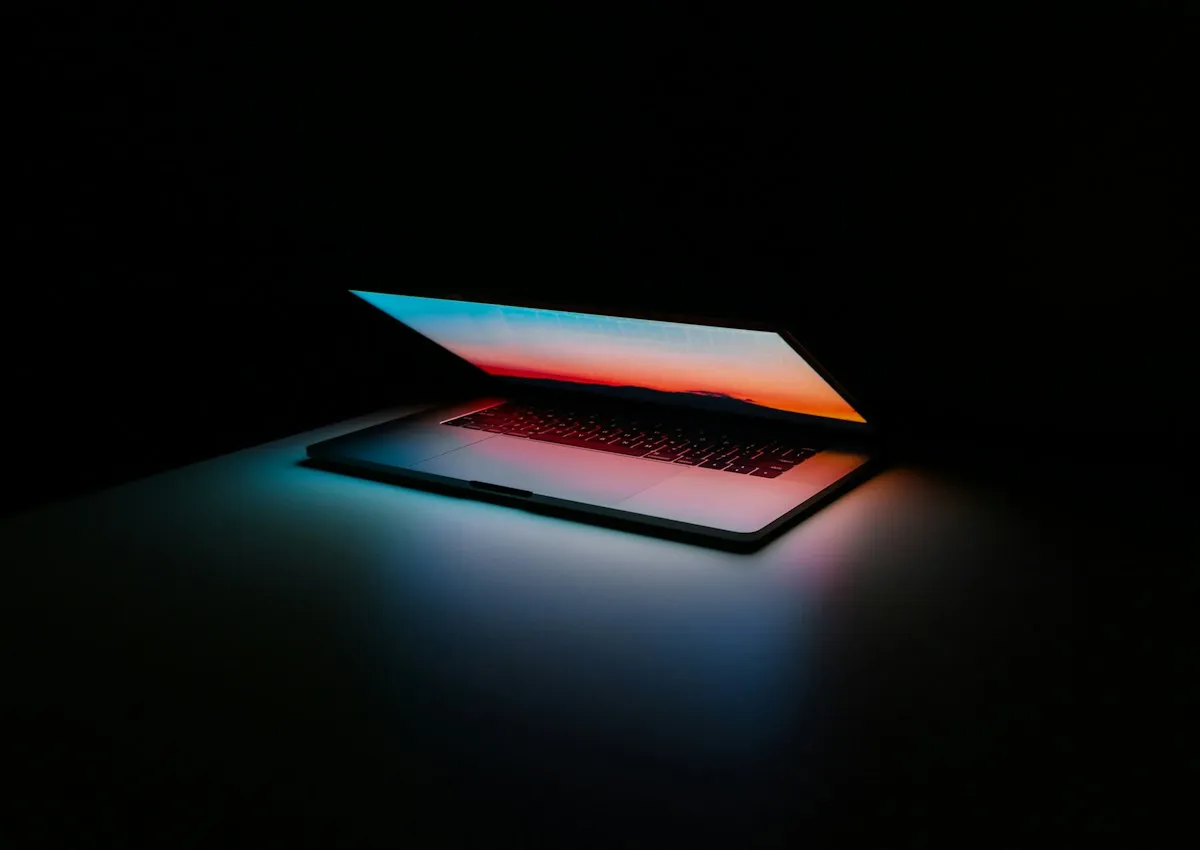 A laptop glowing in a dark workspace