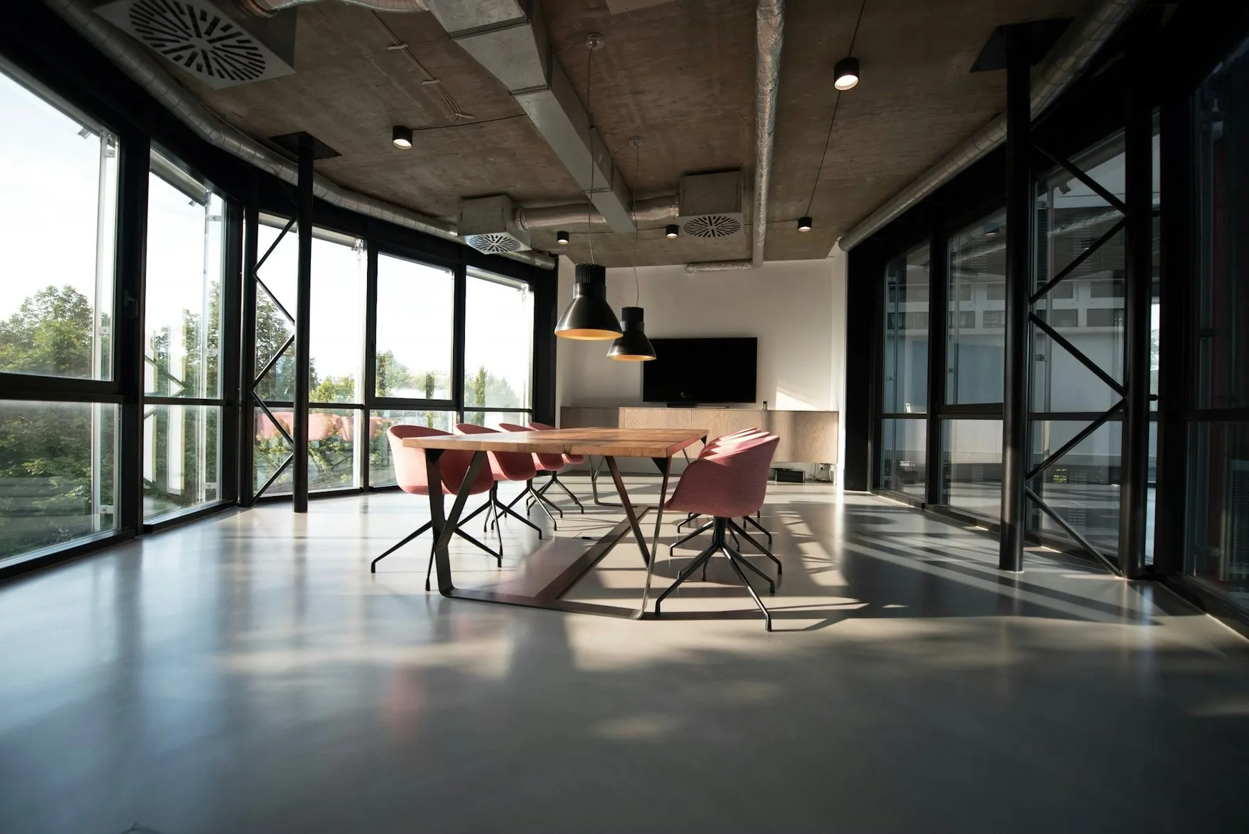 An open-plan office with a long meeting table and floor-to-ceiling windows