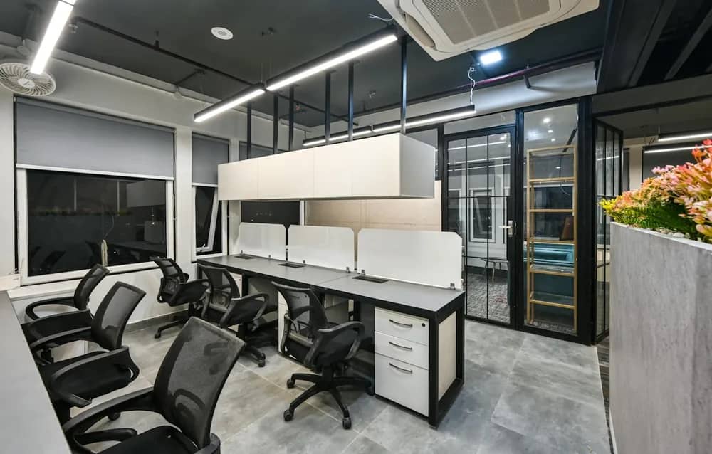 An office with workstations and a glass-walled cabin